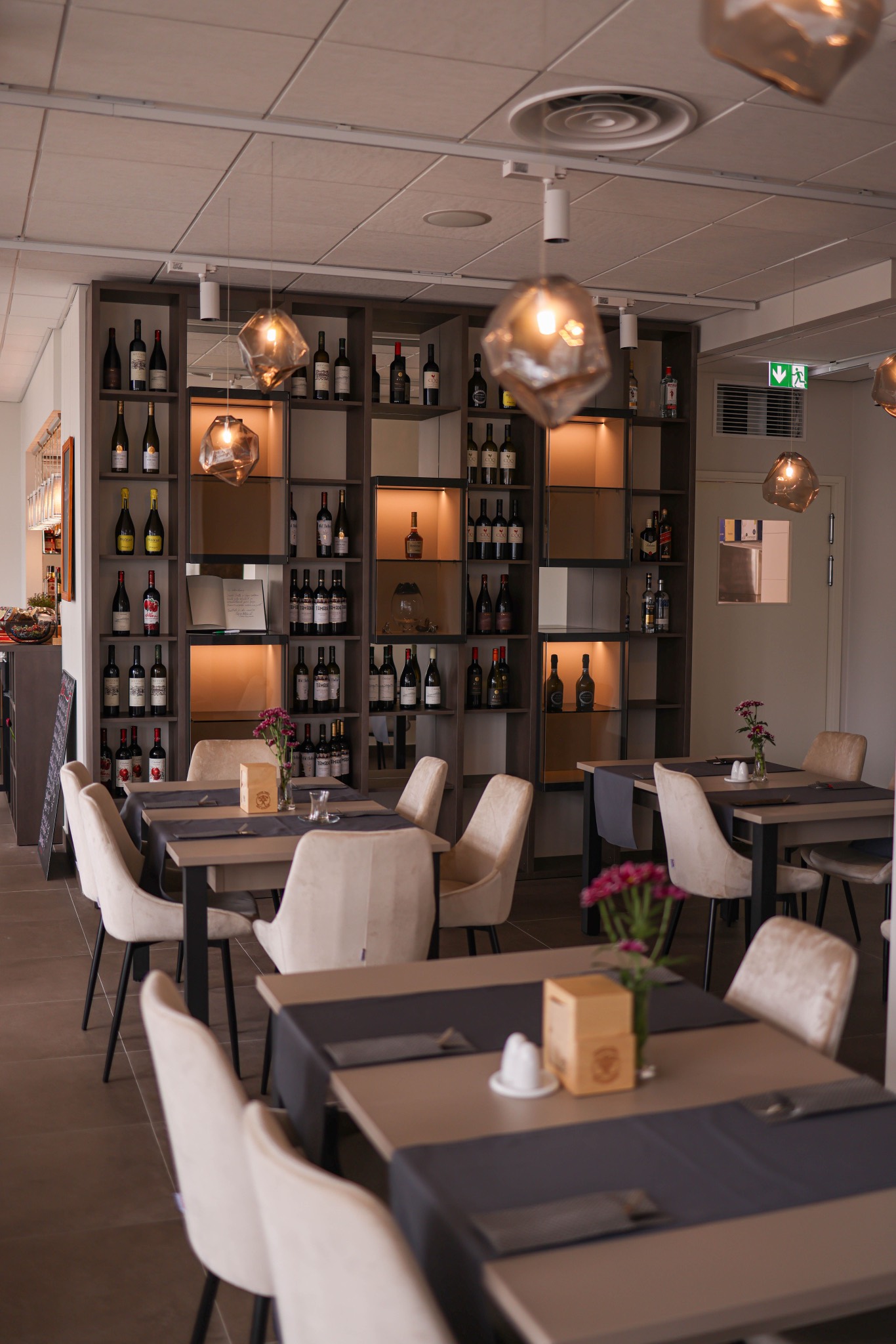 Gedeckte Tische vor dem beleuchteten Weinregal im Bistro zur Linde